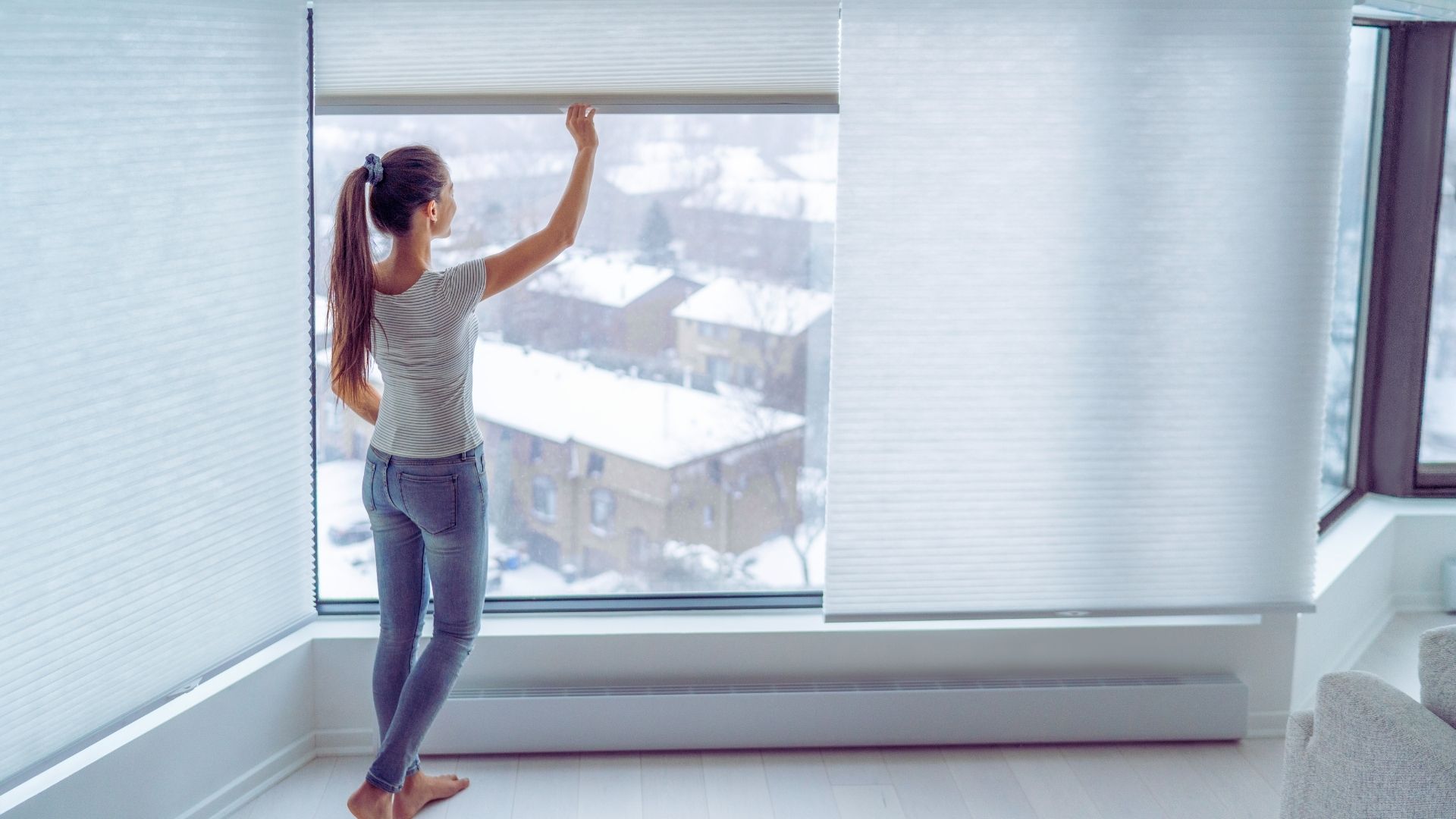 woman closing cellular blinds in modern home