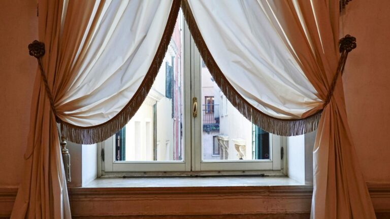 grommet top drapes in michigan hanging drapes by window looking out into european alley way white silky drapes