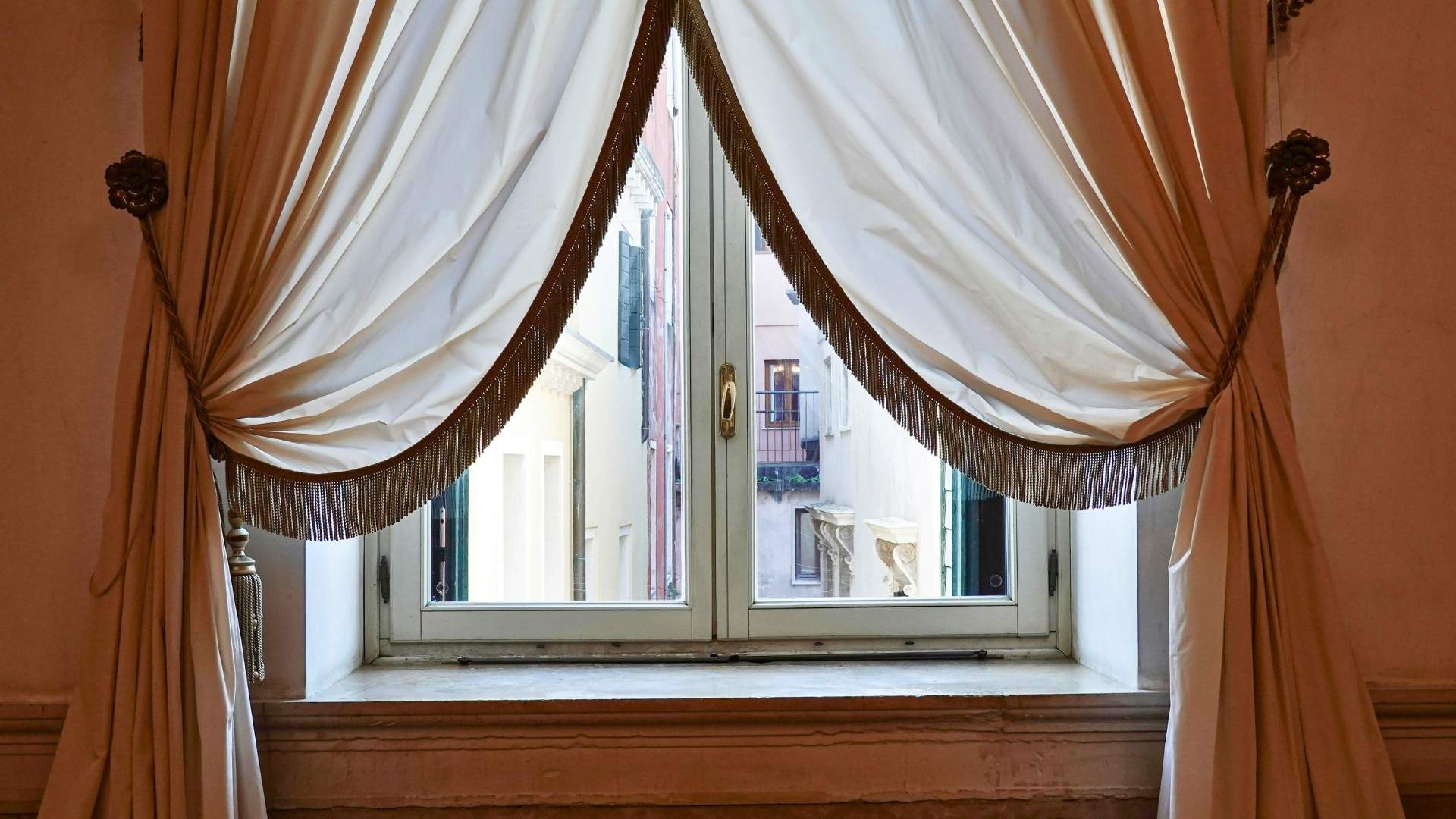 grommet top drapes in michigan hanging drapes by window looking out into european alley way white silky drapes