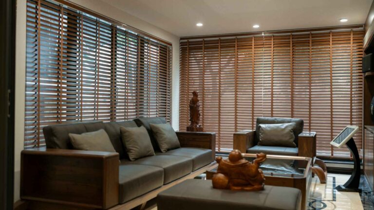 modern living room with a sofa and lounger chair with large windows with wood blinds for cover